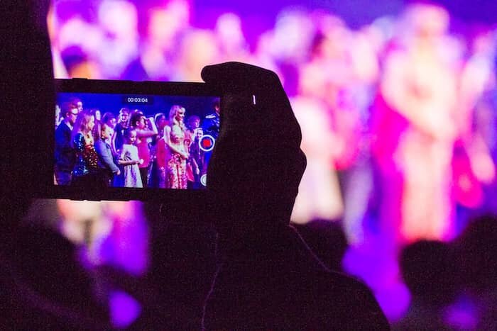 Get More Music Students - Parent filming their kids performing at a huge rock concert